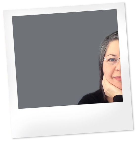 Polaroid of a white woman with dark hair wearing rimless glasses and a black pullover. Only half her face is visible on the right side of the photo.